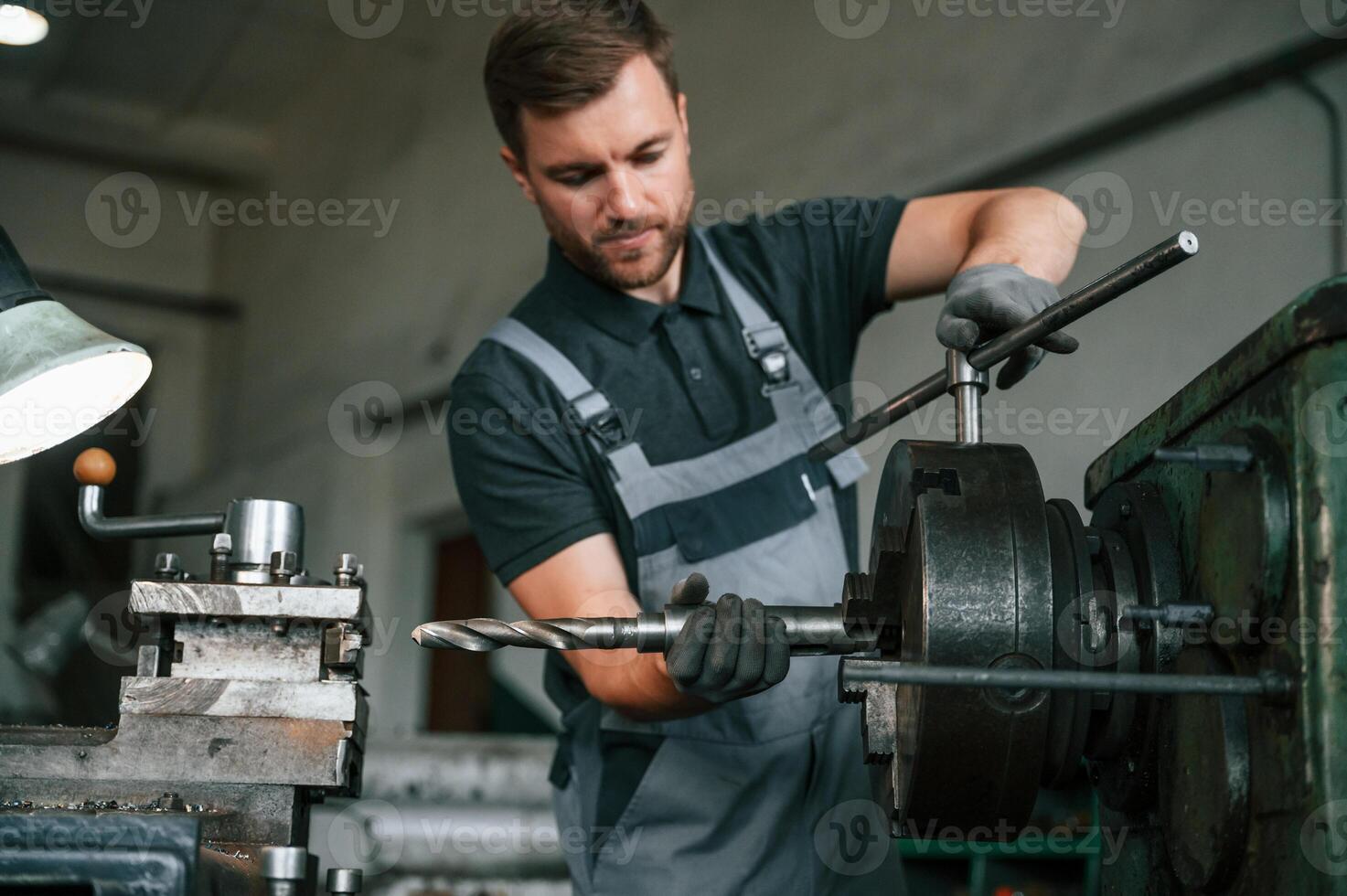 Crafting details. Man in uniform is in workstation developing details of agriculture technique photo