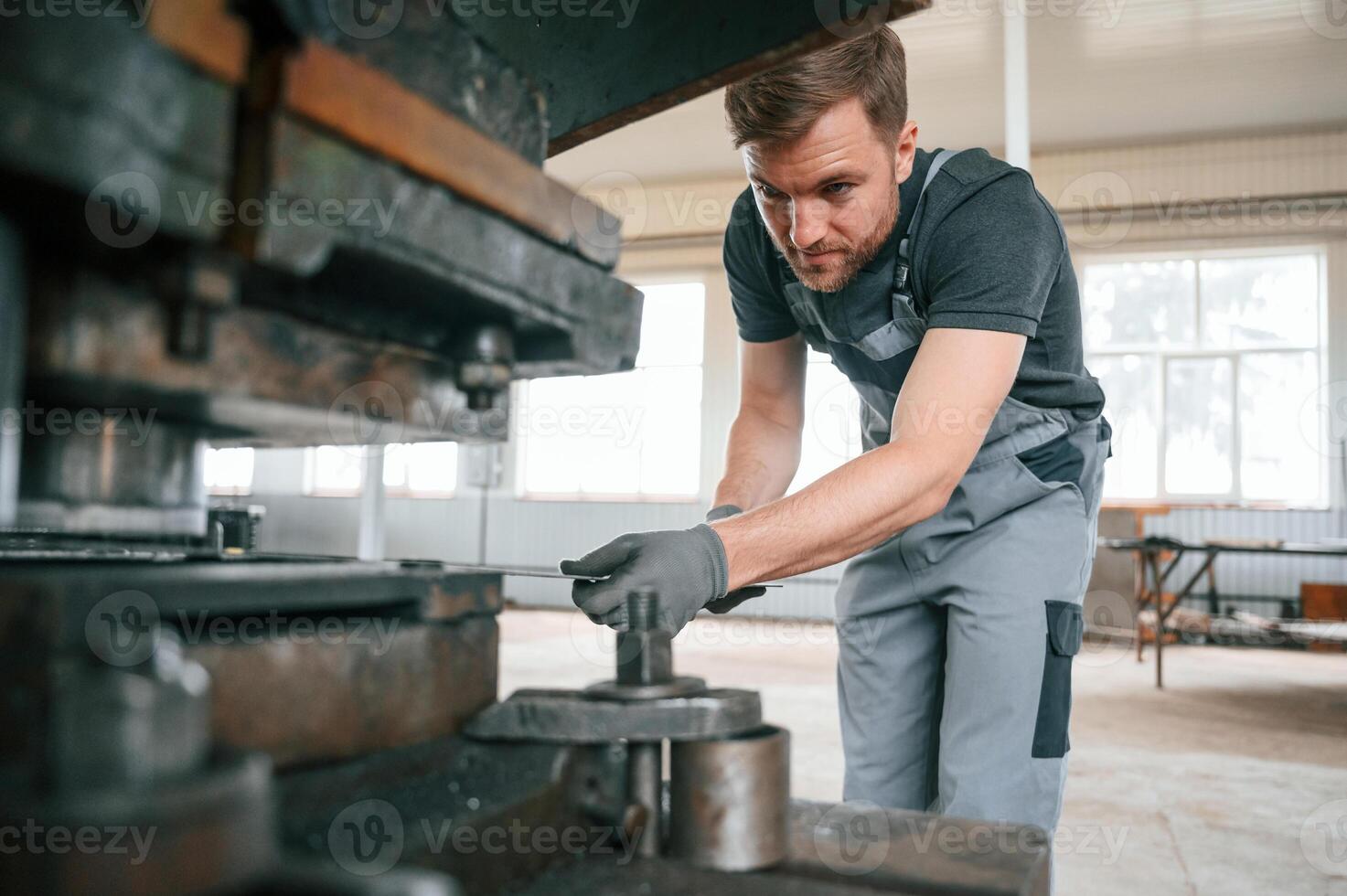 Operating manufacturing equipment. Man in uniform is in workstation developing details of agriculture technique photo