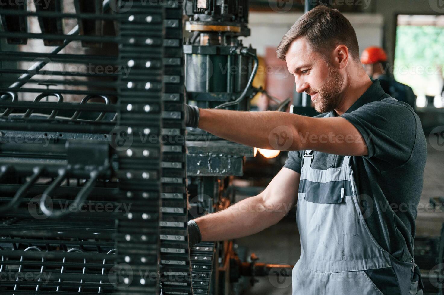 Metal, processing device. Man in uniform is in workstation developing details of agriculture technique photo