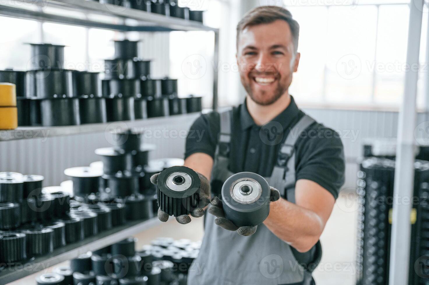 Holding objects and smiling. Man in uniform is in workstation developing details of agriculture technique. photo