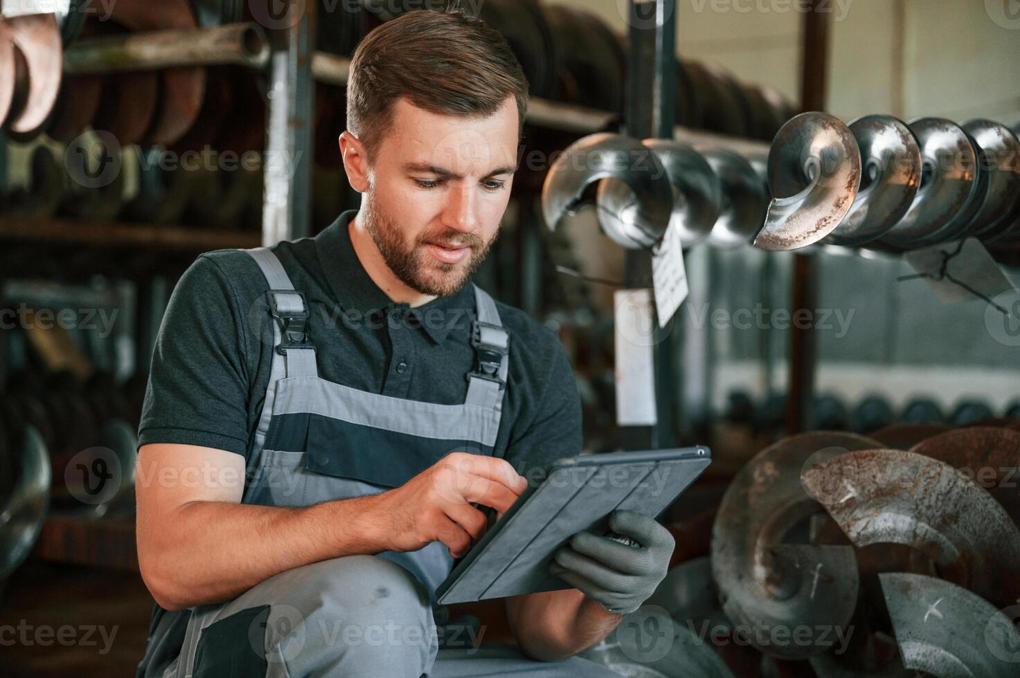 Manager is using digital tablet. Man in uniform is in workstation developing details of agriculture technique photo