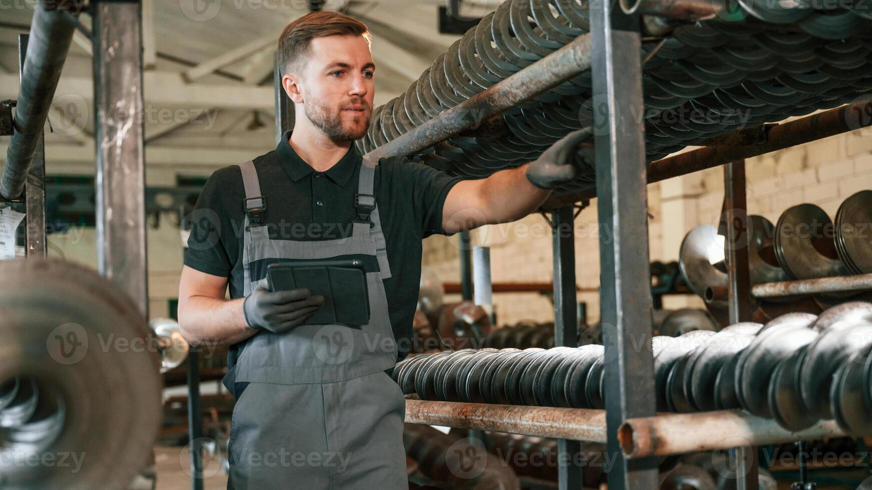 Checking. quality of the products. Man in uniform is in workstation developing details of agriculture technique photo