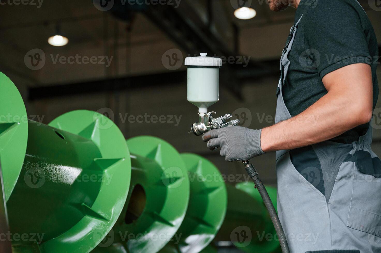 Painting details. .Man in uniform is in workstation developing details of agriculture technique photo