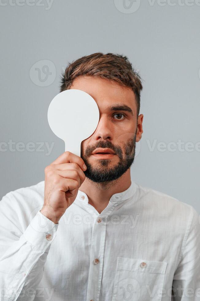 Covering right eye. Man, is checking his vision indoors in the clinic photo