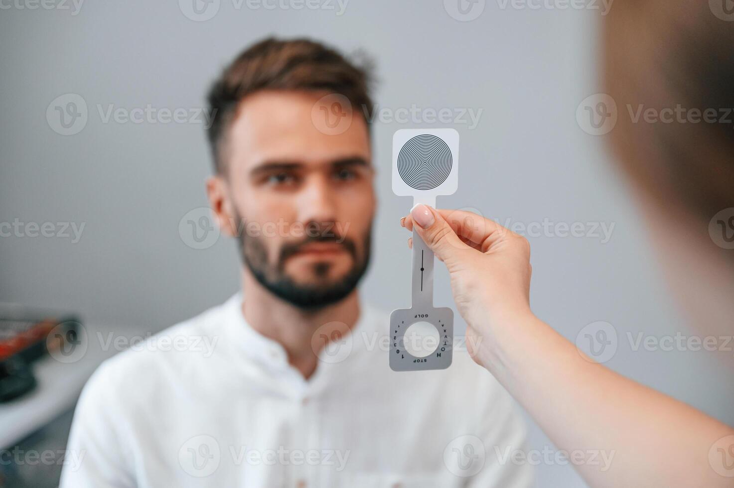 Holding tool. ,Man's vision checked by female doctor in the clinic by using special optometrist device photo
