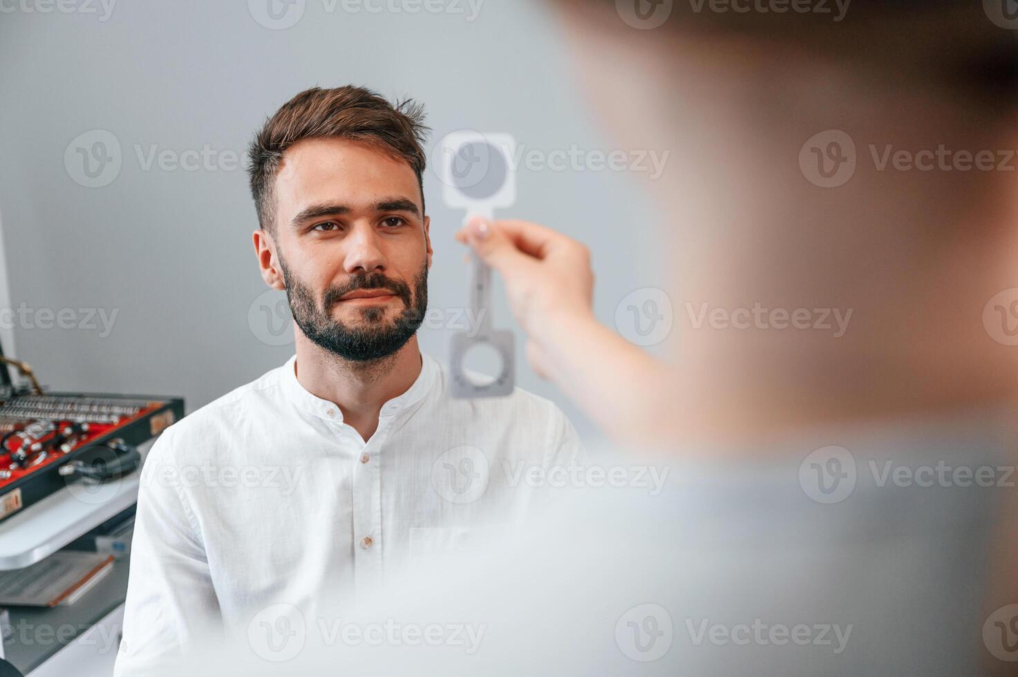 Holding tool. Man's vision checked by female doctor in the clinic by using special optometrist device photo