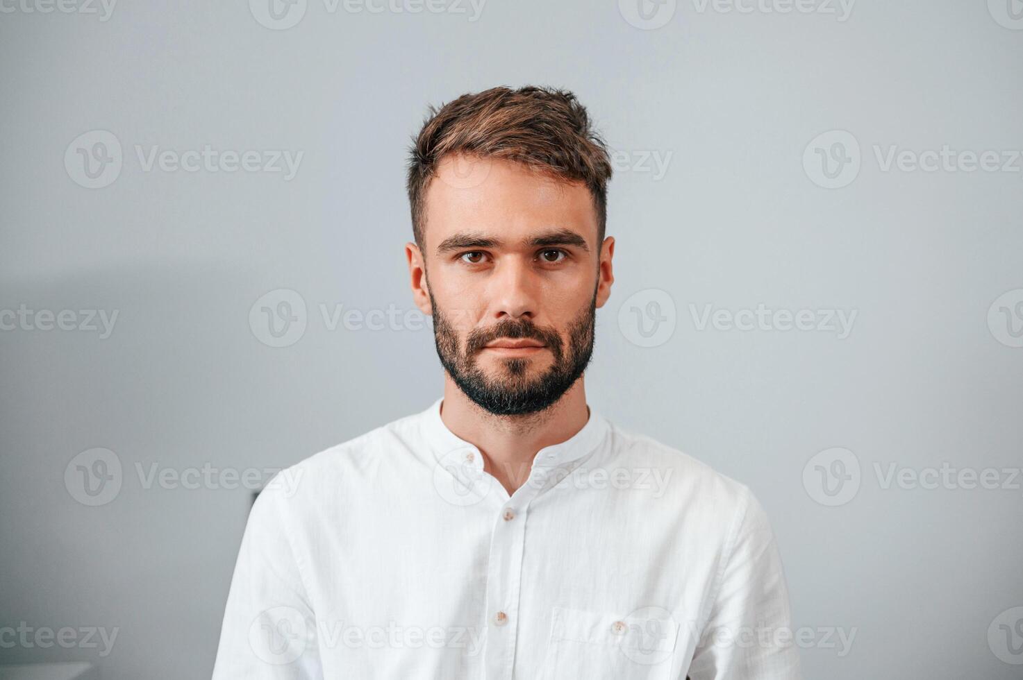 Portrait of stylish young man that standing indoors against wall photo