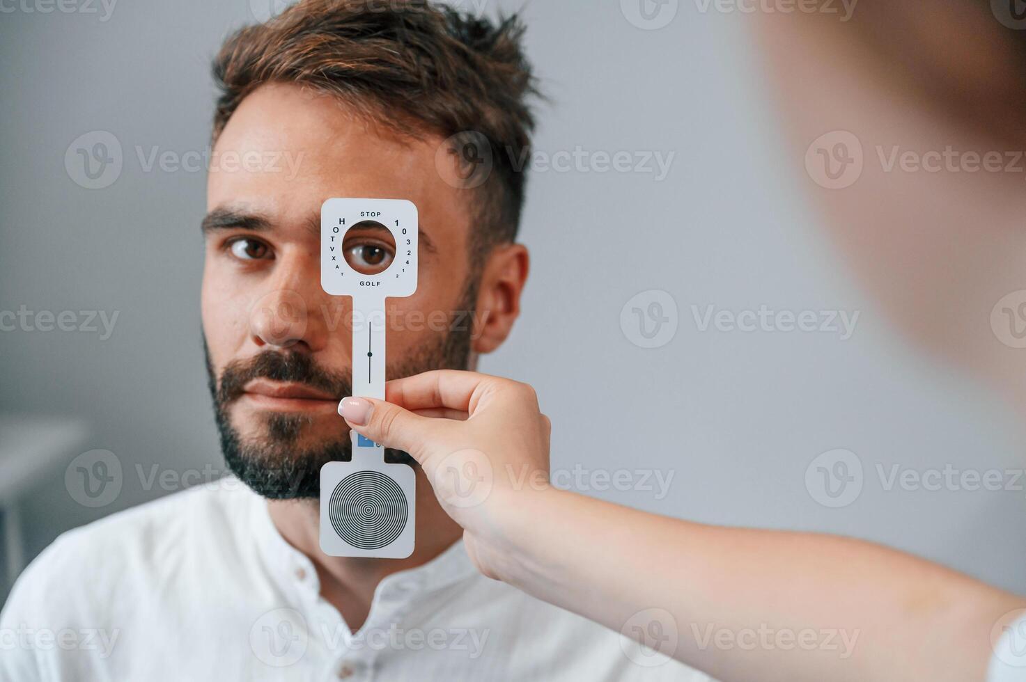 Holding tool.. Man's vision checked by female doctor in the clinic by using special optometrist device photo