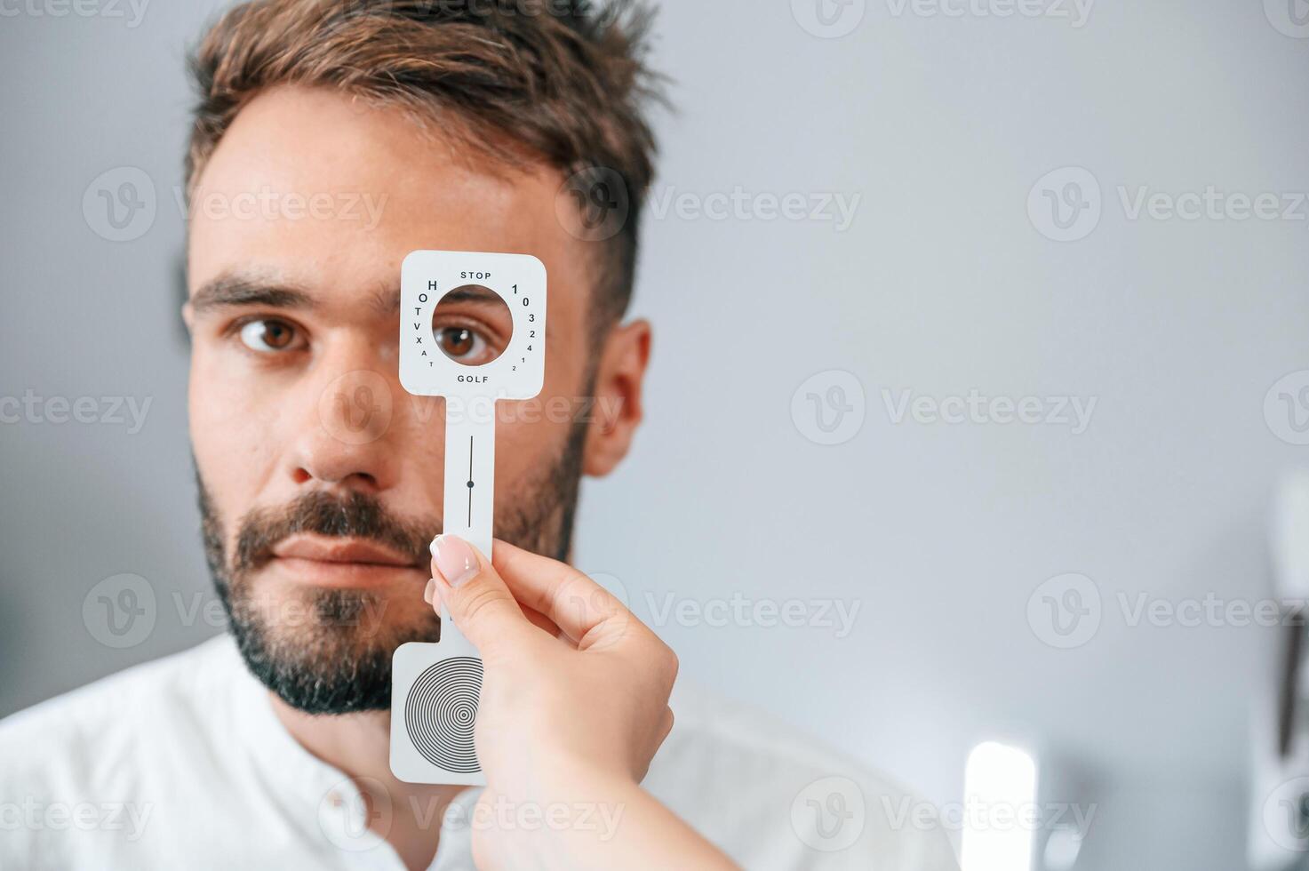 Holding tool., Man's vision checked by female doctor in the clinic by using special optometrist device photo