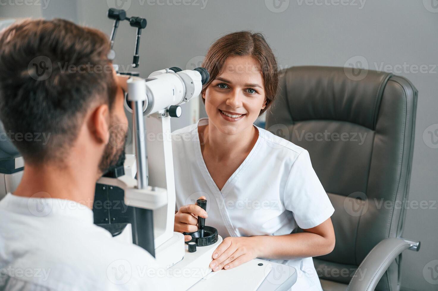 Modern technologies.. Man's vision checked by female doctor in the clinic by using special optometrist device photo