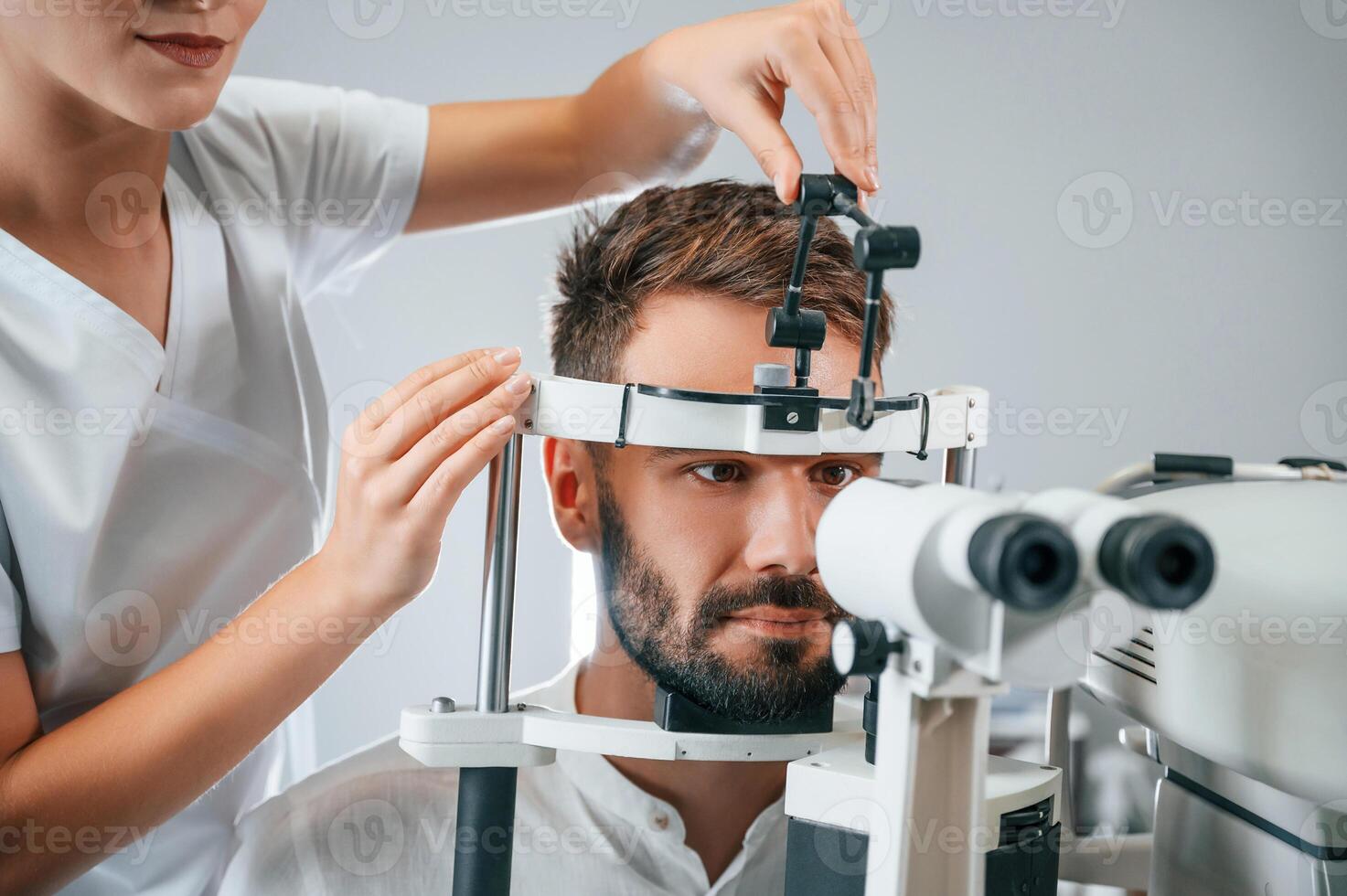 Man's vision ,checked by female doctor in the clinic by using special optometrist device photo