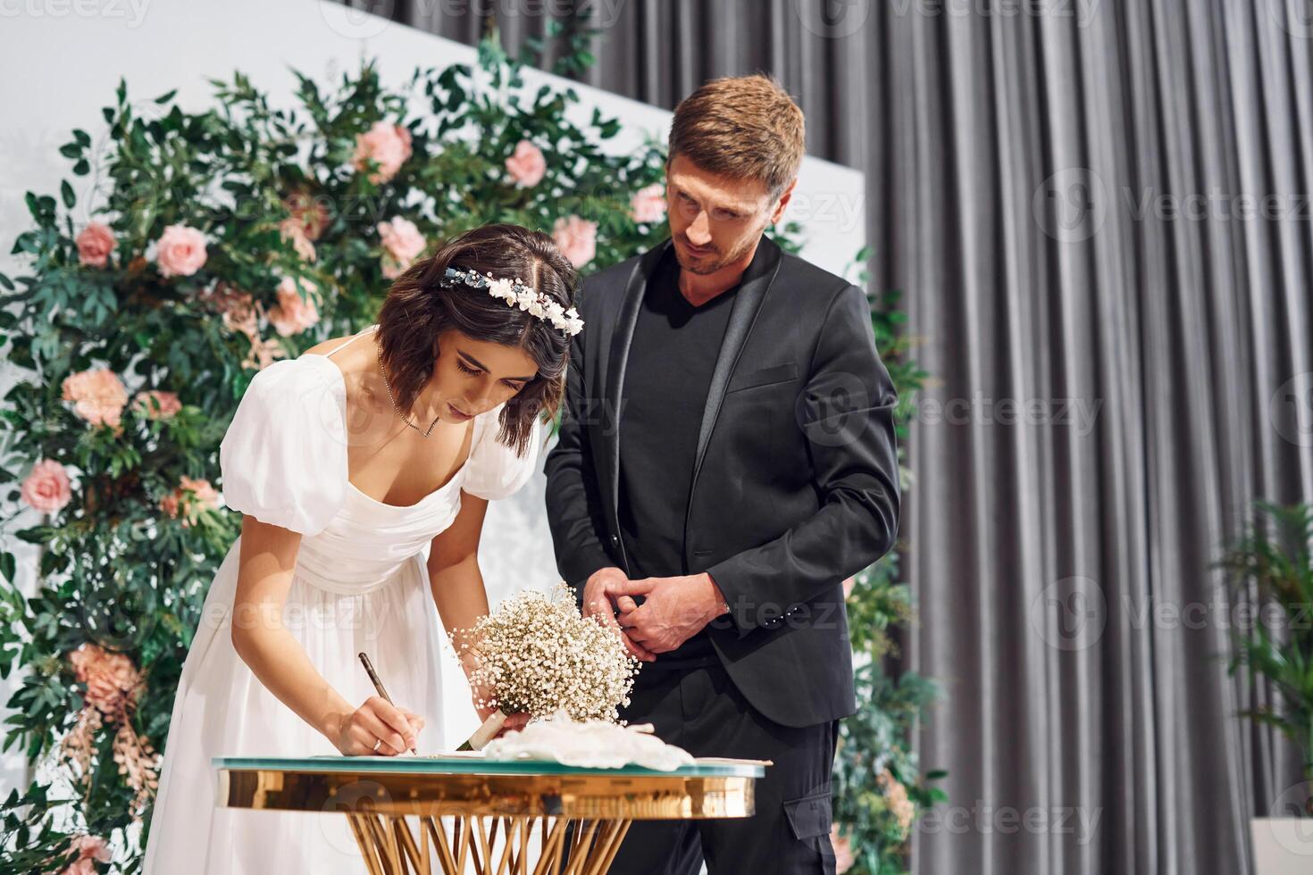 Signs the marriage document. Beautiful bride with his fiance is on the wedding photo