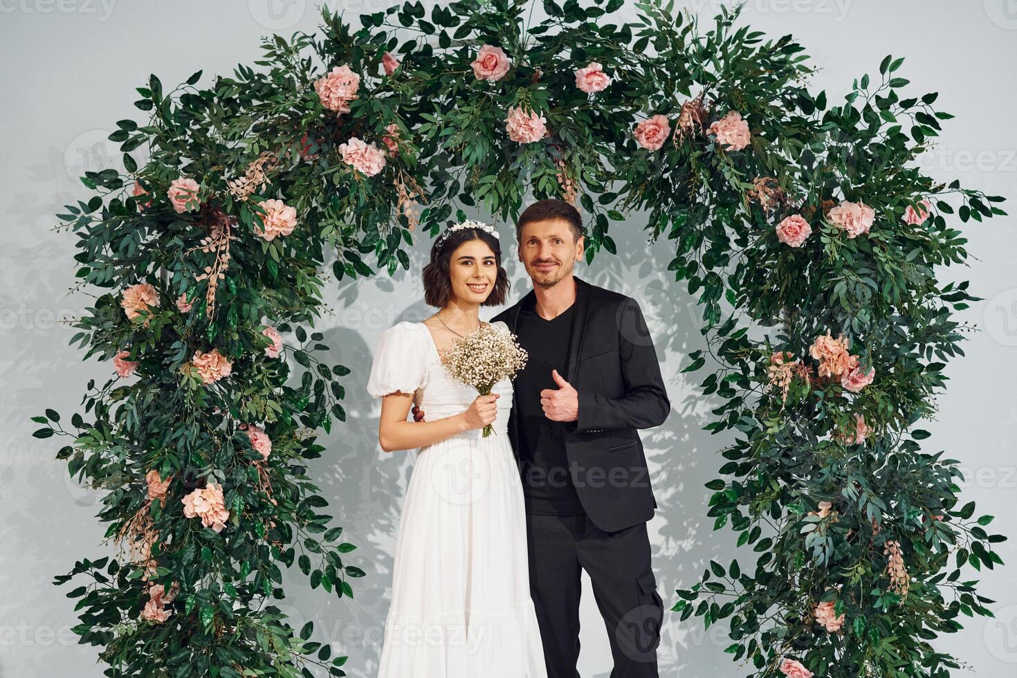 Standing against flowers. ,Beautiful bride with his fiance is on the wedding photo