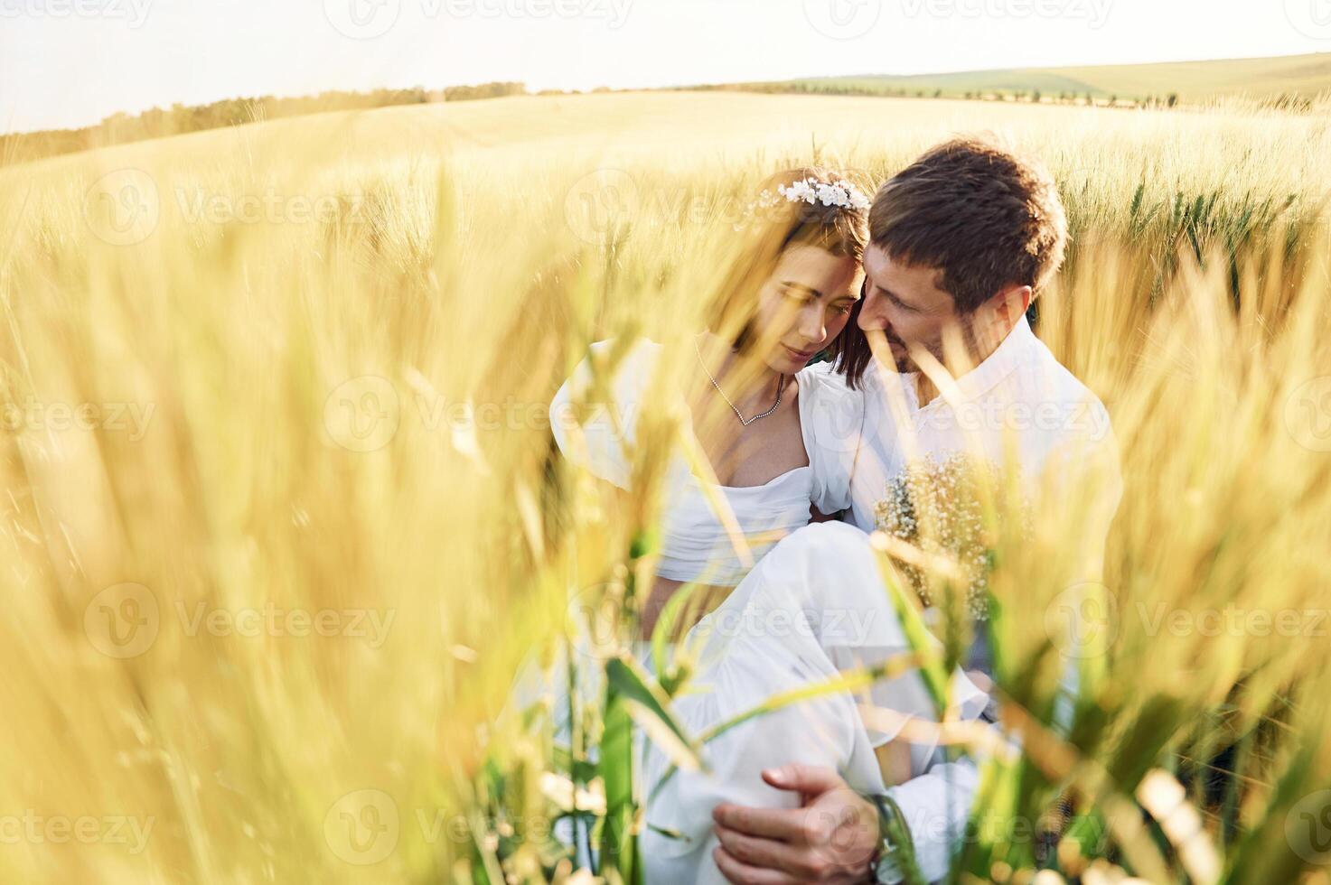 Sitting in the wheat. Happy people. Couple just married. Together on the majestic agricultural field at sunny day photo