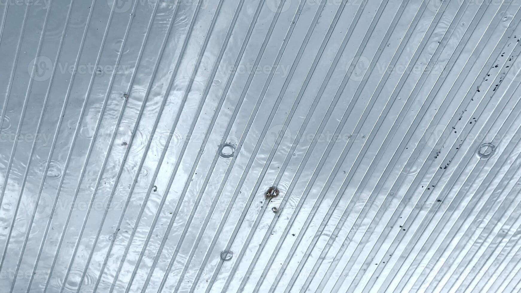 Heavy rain drumming on the transparent plexiglass roof. Beautiful rainy scene on summer day. Concept of tranquility nature scene. Close up Slow motion photo
