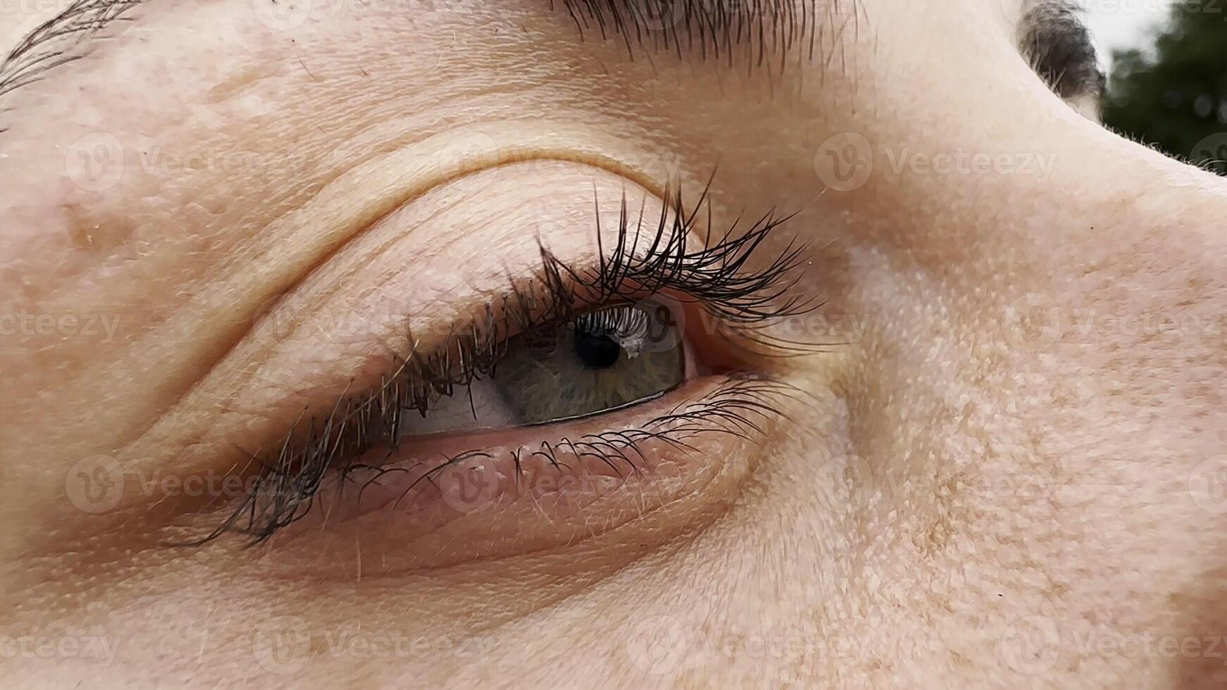 Focus on right green eye of attractive girl blinking and looking into camera. Portrait of upset female face. Sorrowful facial expression of young woman. Unhappy sight of beautiful lady. Close up photo