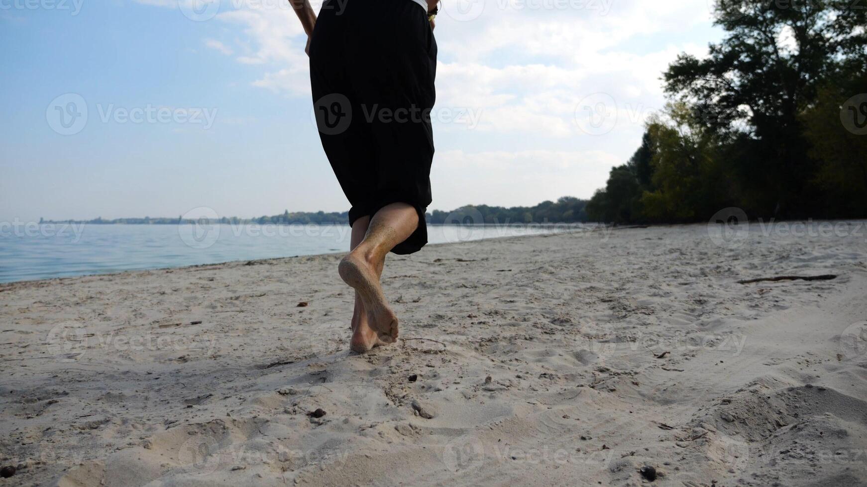 Bare feet of adult woman jogging on sand at the beach with seascape at background. Female legs running along sea shore. Happy lady spending time near ocean coast. Concept of summer vacation photo
