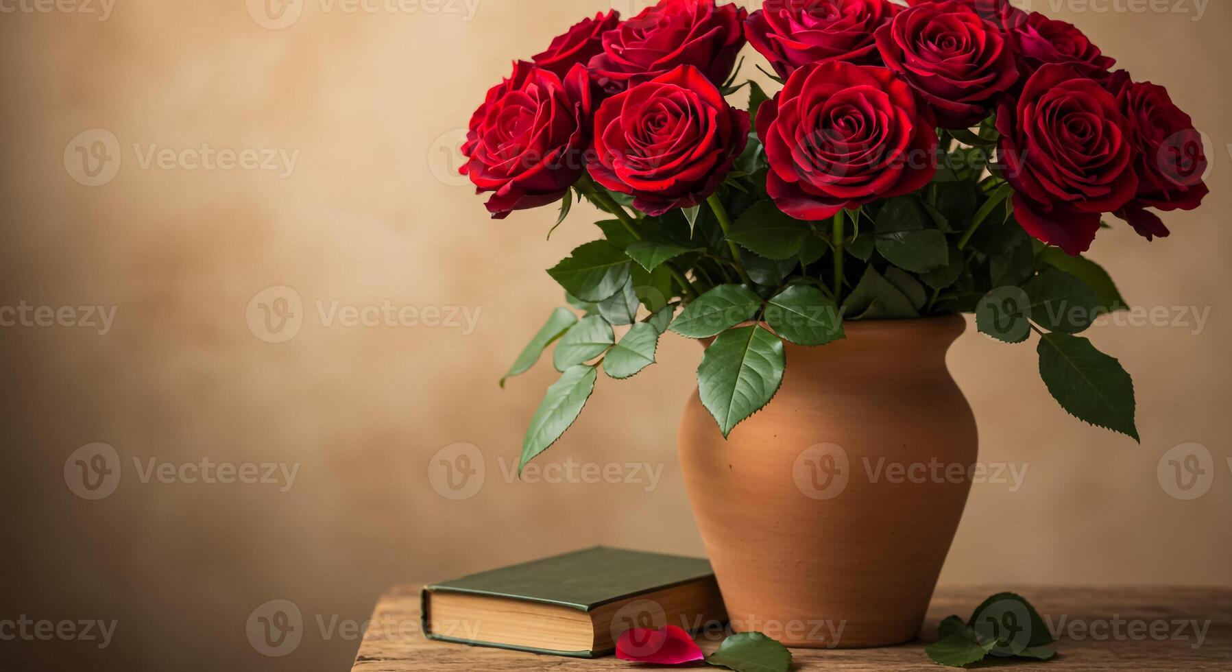 A vase with red roses sitting on a table next to a book photo