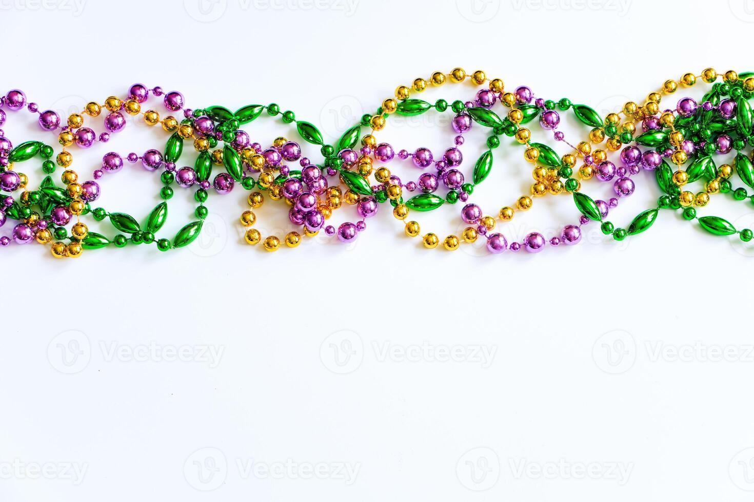 Mardi Gras background. Gold, green and purple beads on white background. Fat Tuesday symbol photo