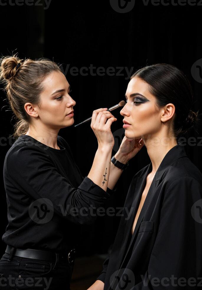 makeup artist applying eyeshadow to beautiful woman, isolated on black. Makeup Artist Applying Smokey Eye photo