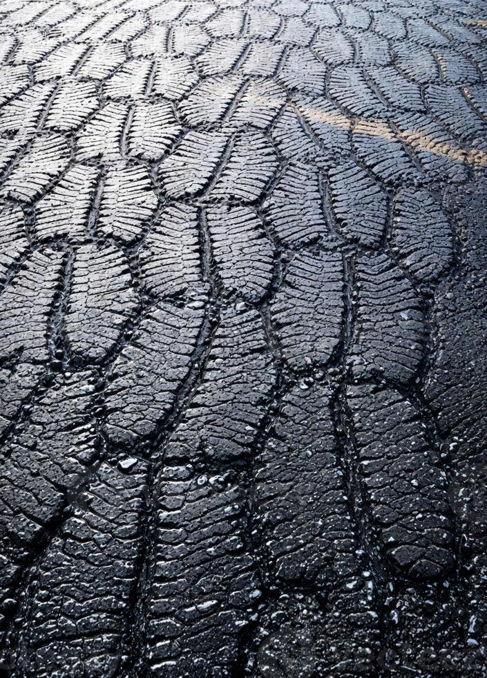 Tire tracks on the asphalt road in the rain. Toned. Cracked Asphalt Road Surface photo
