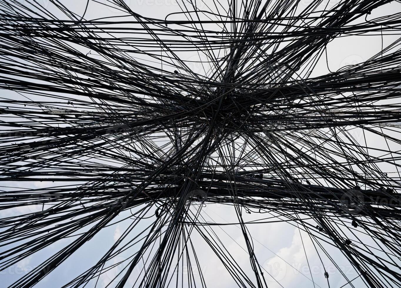 Abstract background of tangled wires and blue sky with white clouds in the background. Tangled City Cables photo