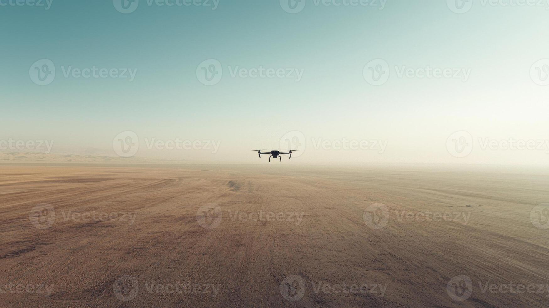 A small drone flying over a desert area photo