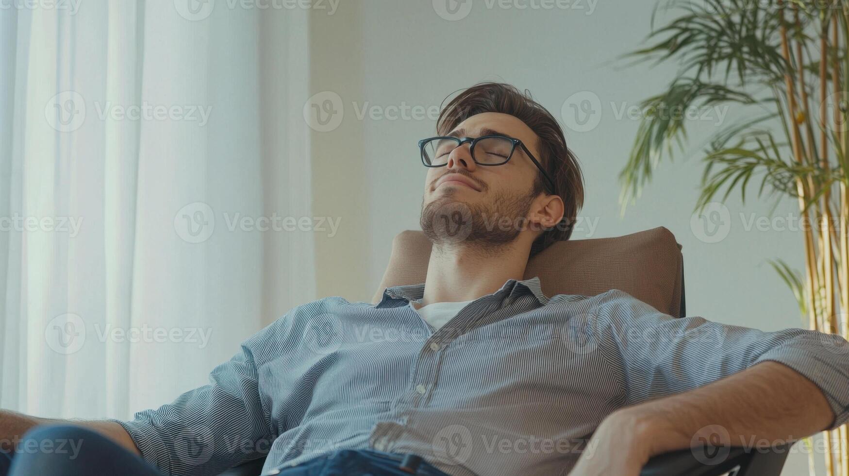 A man in glasses is relaxing in a chair photo