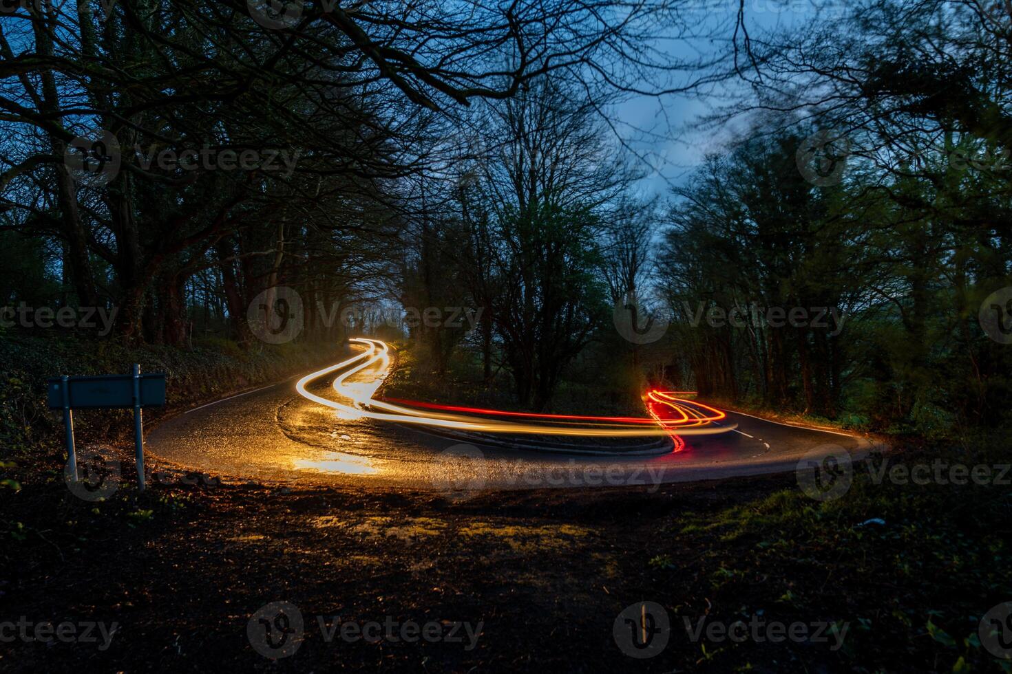 Curved road with light trails at twilight photo
