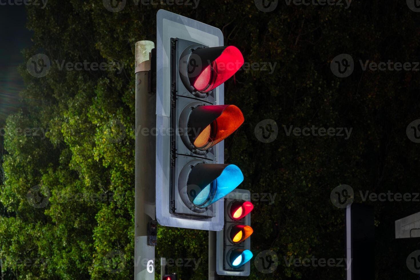 Traffic light showing red, orange and blue signals at night photo