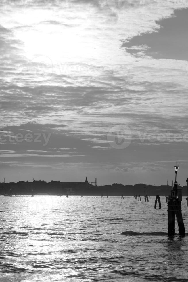 Sun shining over the venetian lagoon with dramatic sky in black and white photo