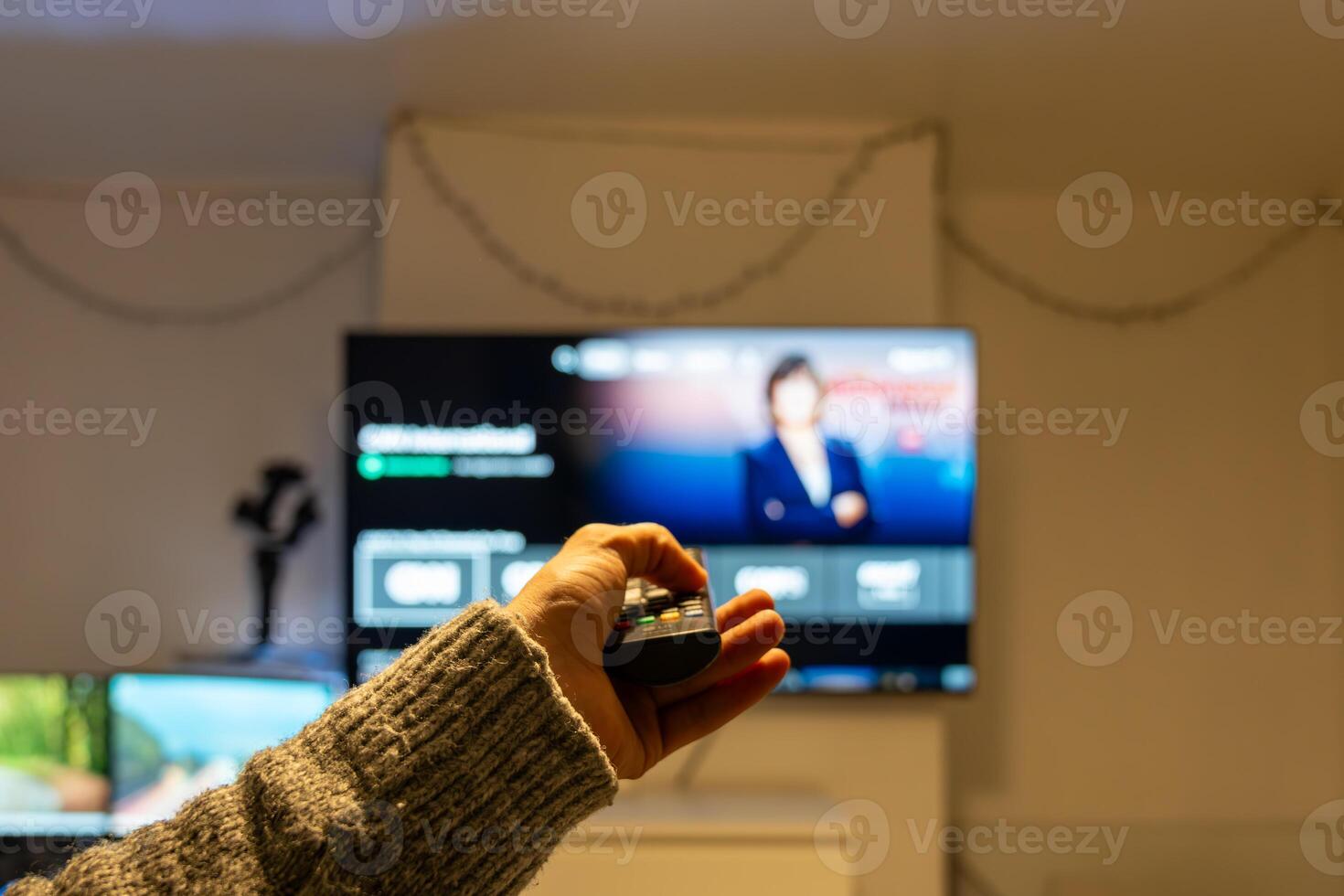 Man using remote control, changing channels on television, watching news photo