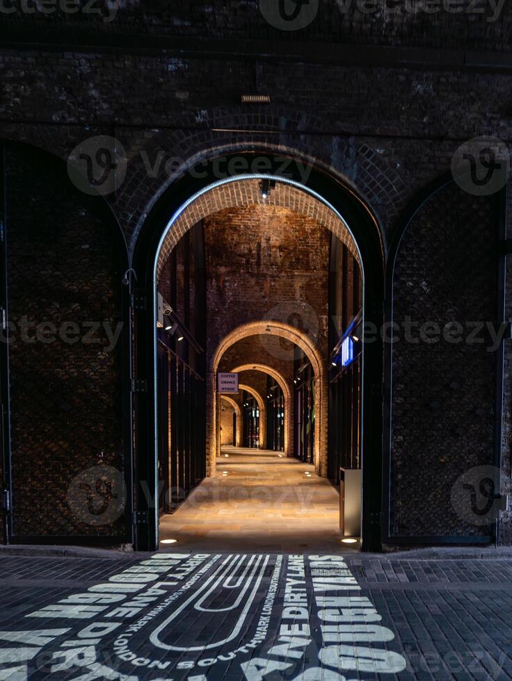 Empty illuminated brick archway walkway leading to shops photo