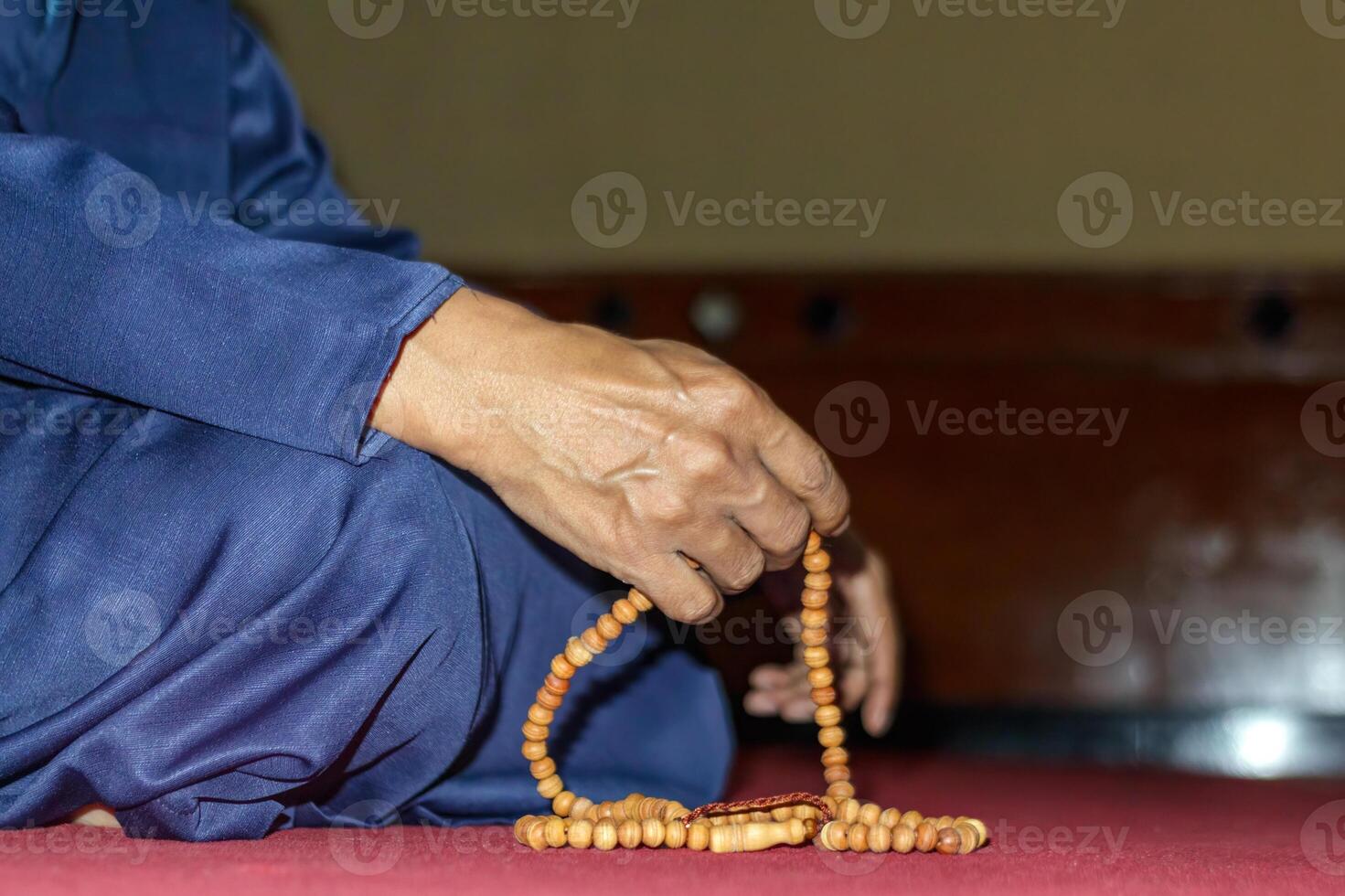 Man Praying with Wooden Beads in Mosque photo