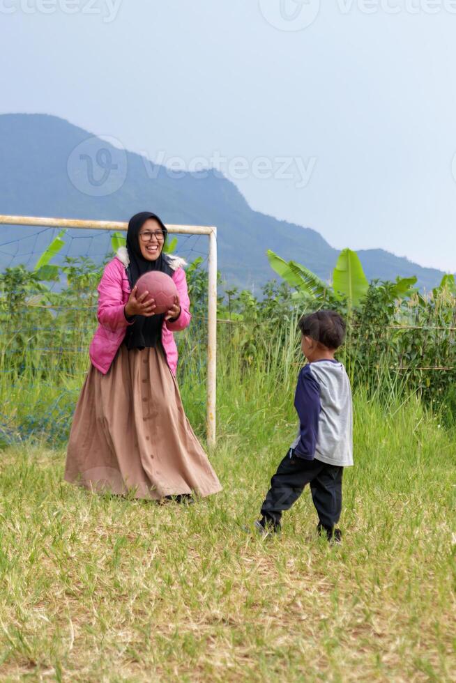 Mother and Son Playing Soccer in a Rural Field photo