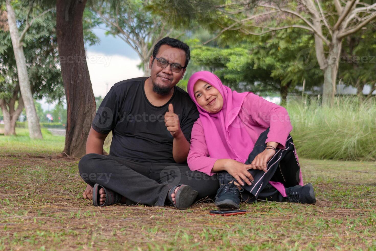 Happy Muslim Couple Relaxing in a Green Park photo