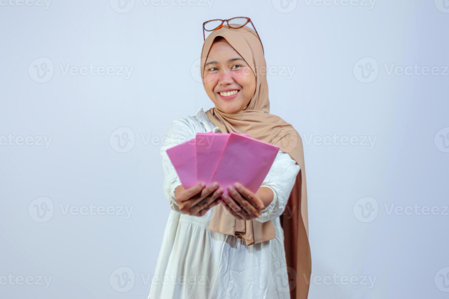 Smiling Muslim Woman Holding Pink Envelopes for Celebration photo