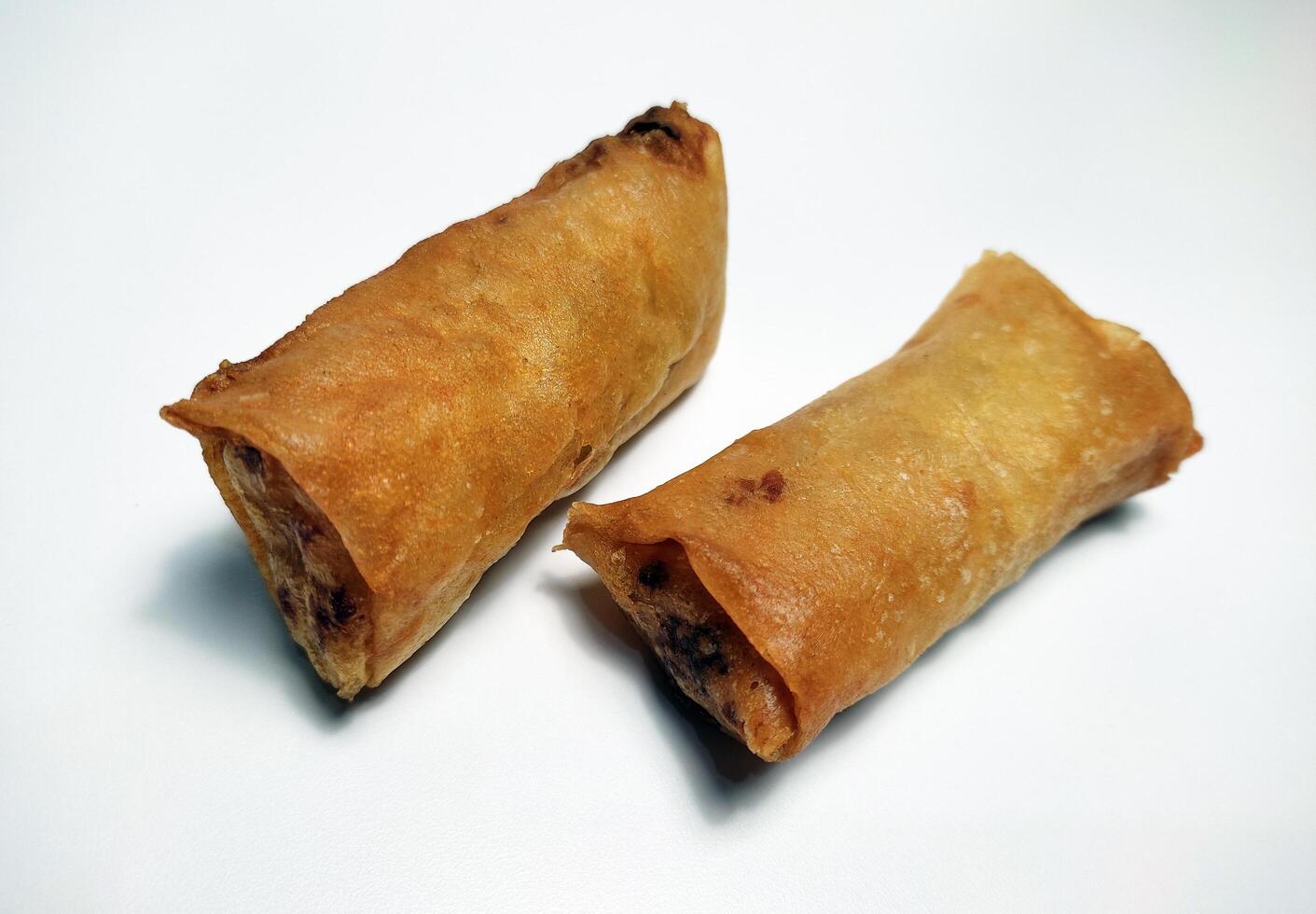 Fried spring rolls or lumpia, typical Indonesian snack, on a patterned plate, isolated in white background photo