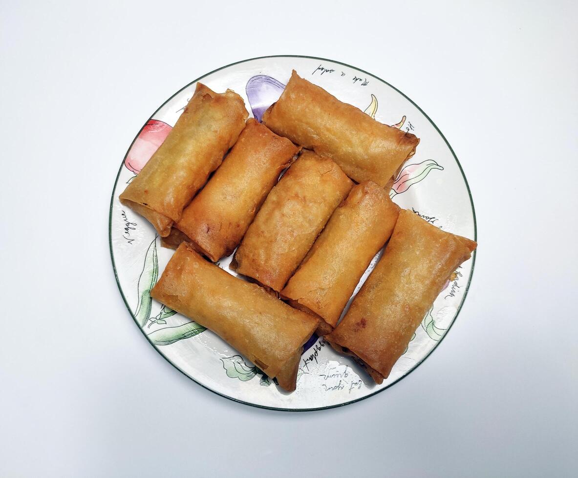 Fried spring rolls or lumpia, typical Indonesian snack, on a patterned plate, isolated in white background 4 photo