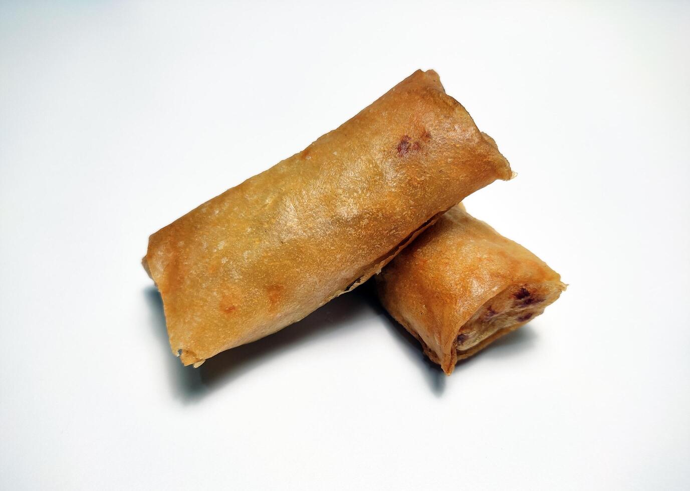 Fried spring rolls or lumpia, typical Indonesian snack, on a patterned plate, isolated in white backgrounds photo