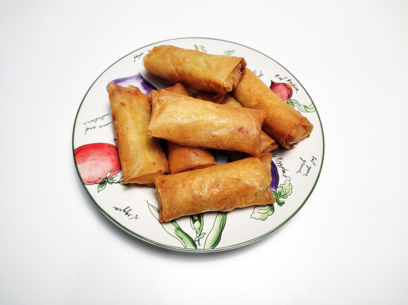 Fried spring rolls or lumpia, typical Indonesian snack, on a patterned plate, isolated in white background 3 photo