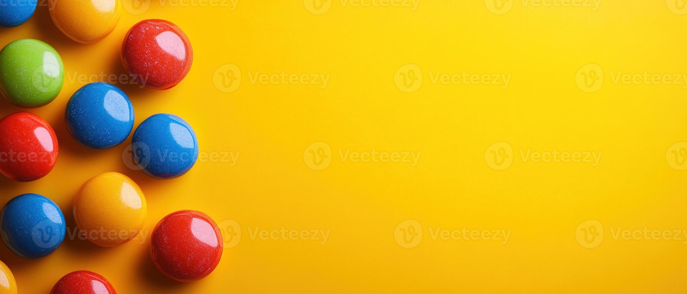 Flat Lay of Glossy Colorful Candies on a Bright Yellow Background with Copy Space photo