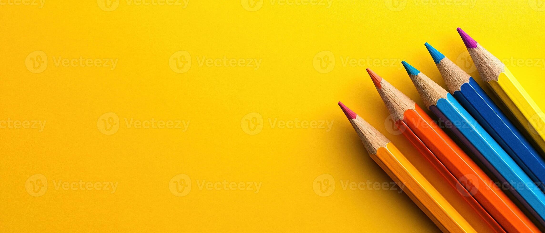 Vibrant Wooden Colored Pencils with Sharp Tips Arranged on a Bright Yellow Background with Copy Space photo