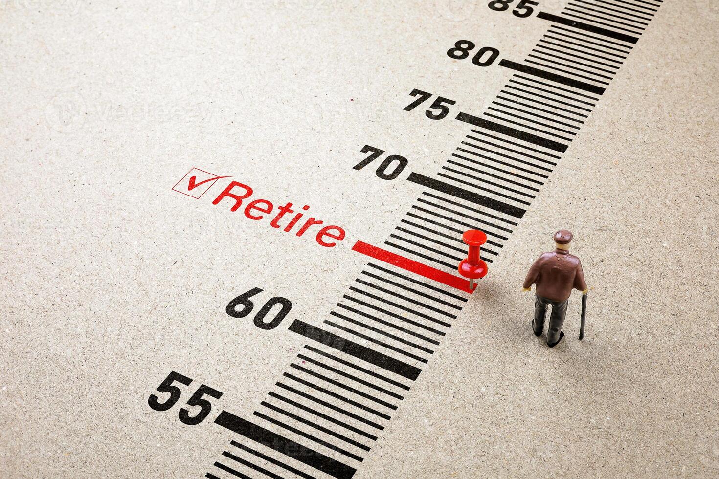 Red pin on retire scale with little senior man doll on paper background. Concept of retirement planning finance, health insurance and living a happy and secure retirement life. photo