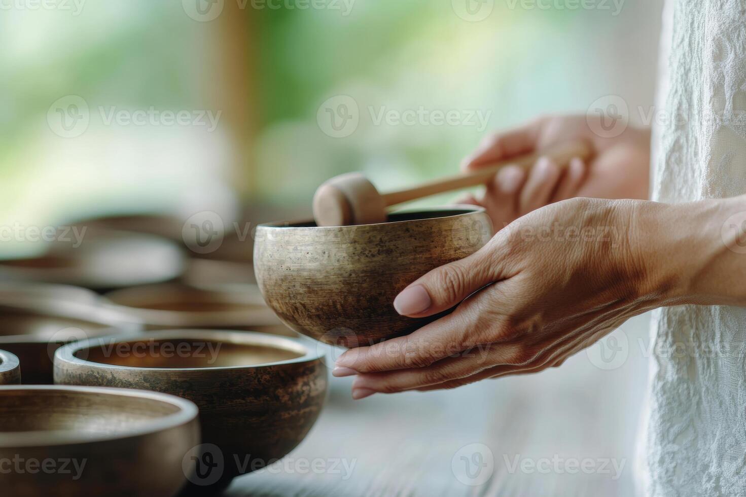 Hands Playing Singing Bowl in Peaceful Meditation Setting with Natural Background photo