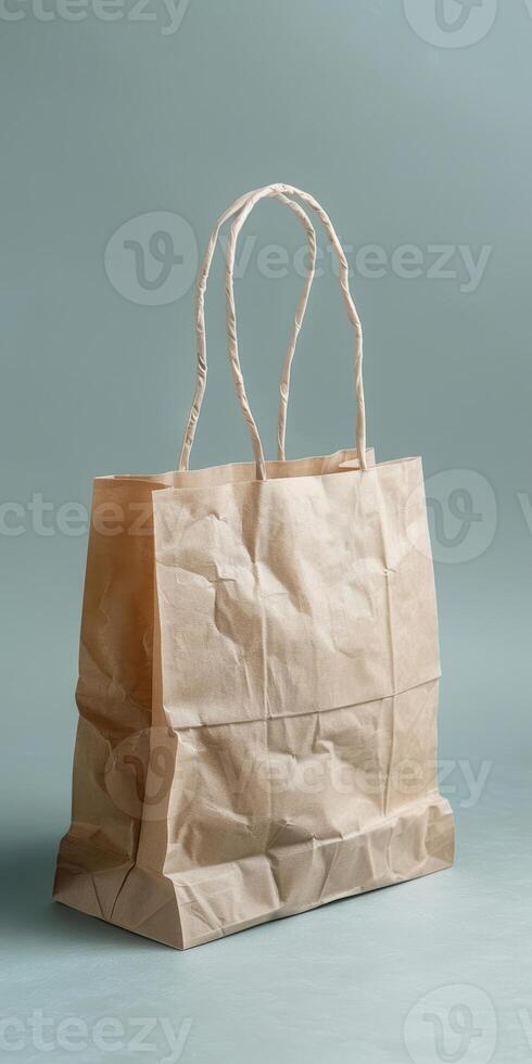 Crumpled brown paper shopping bag with handles on light background photo