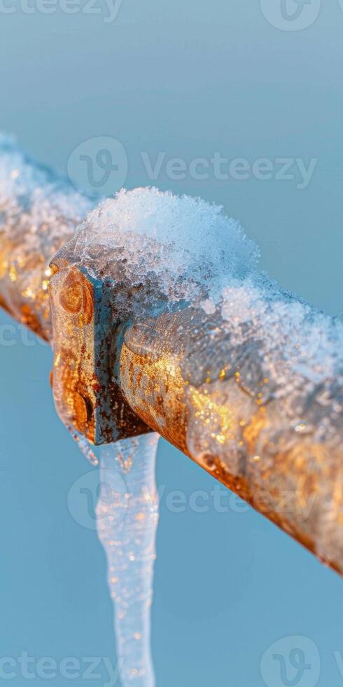 Rusty Metal Pipe with Icicles and Snow in Winter Setting at Sunset photo