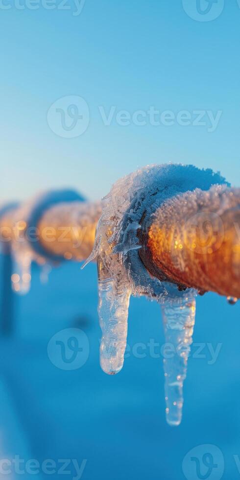 Icy Pipeline in Winter Landscape with Frozen Icicles and Clear Blue Sky at Sunrise photo