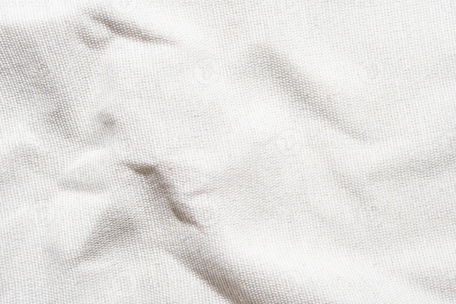 Close-up texture of white wrinkled canvas fabric with subtle shadows. photo
