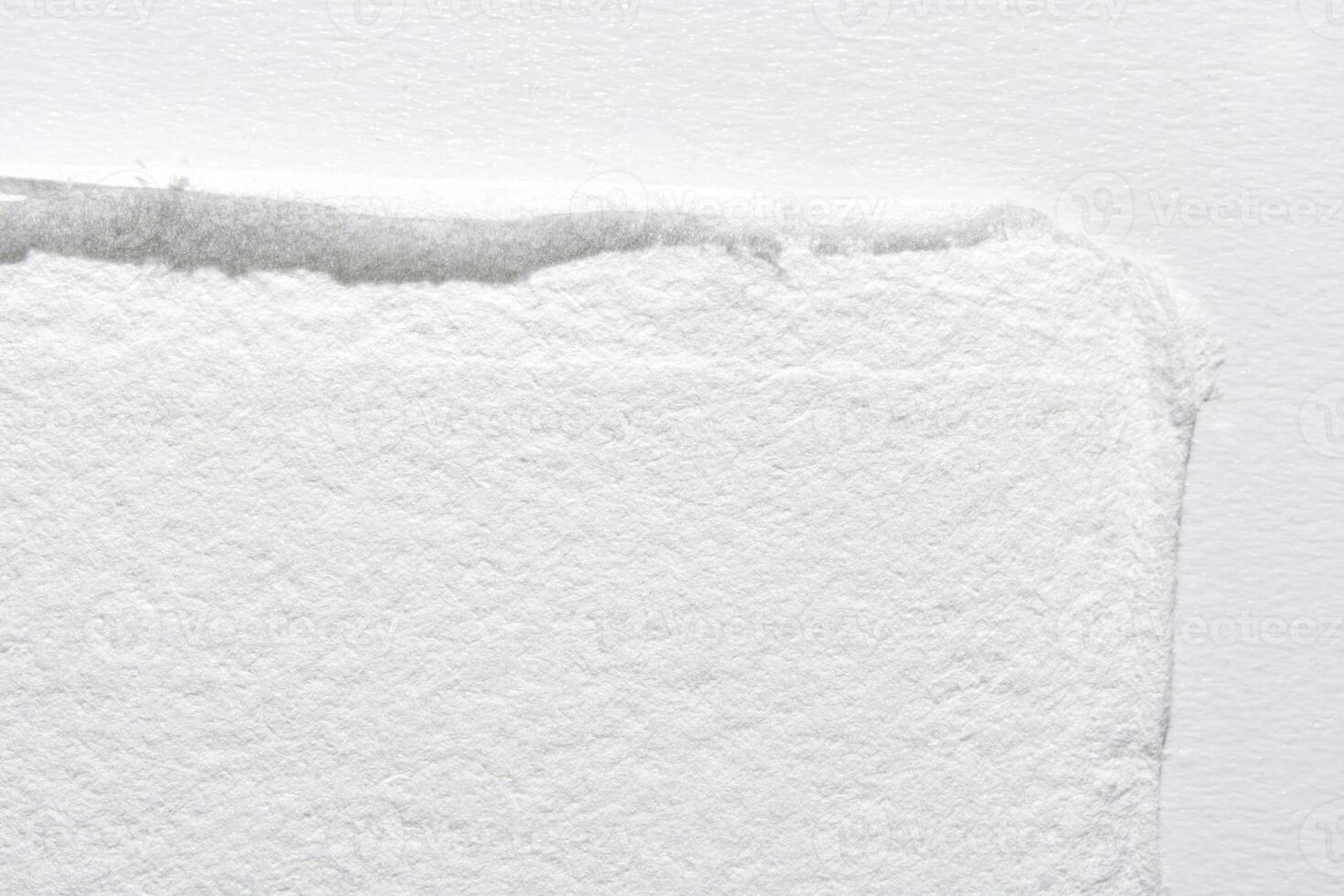 Close-up of textured white paper edge with subtle shadow on light background. photo
